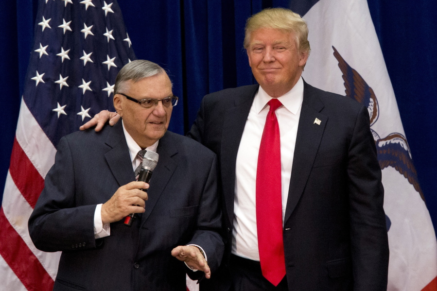 In this Jan. 26, 2016, photo, Republican presidential candidate Donald Trump is joined by Maricopa County, Ariz., Sheriff Joe Arpaio at a campaign event in Marshalltown, Iowa. President Trump says he may grant a pardon to former Sheriff Joe Arpaio following his recent conviction in federal court, prompting outrage among critics who say the move would amount to an endorsement of racism.
