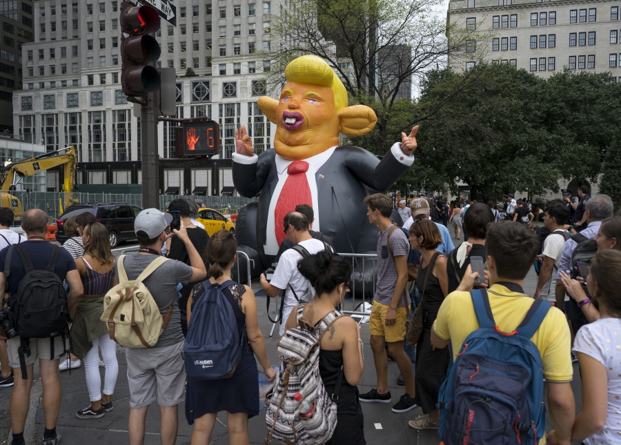 An inflatable caricature of President Donald Trump rises above pedestrians at W. 59th Street and 5th Ave. in New York Monday, Aug. 14, 2017, just three blocks north of Trump Tower.