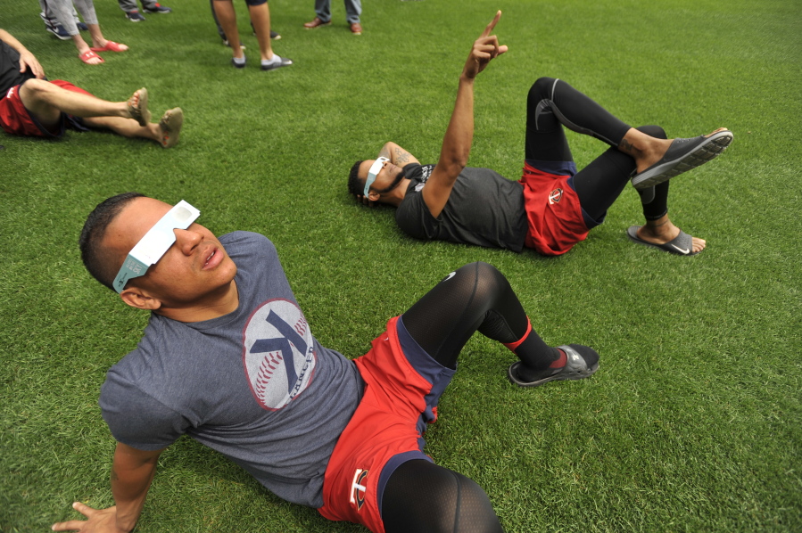 Minnesota Twins players Ehire Adrianza front, and Ervin Santana back, along with other members of the team watch the solar eclipse before a baseball game between the Minnesota Twins and Chicago White Sox Monday, Aug. 21, 2017, in Chicago.