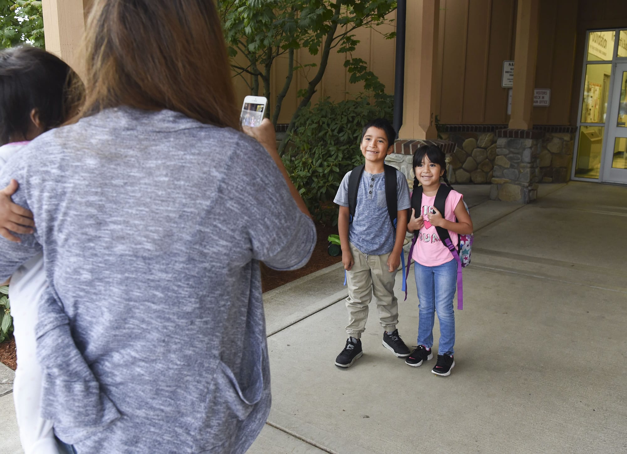 Rosa Garcia, left, takes a photo of her children, Alejandro Ramirez-Garcia, a third-grader at Fruit Valley Elementary School, center, and kindergartener Adamaris Ramirez-Garcia at the entrance of Fruit Valley on the first day of school Wednesday in Vancouver.