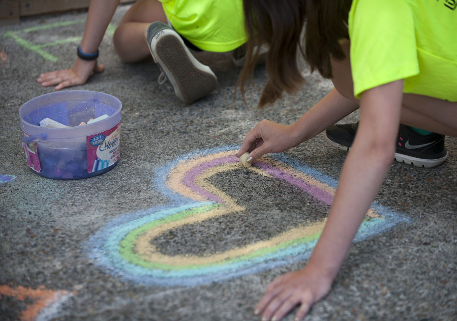 Alexandra Lafayette of Vancouver, member of The Joy Team, draws a heart during The Joy Team’s annual Chalk the Walks in 2016. This year’s event is on Tuesday.