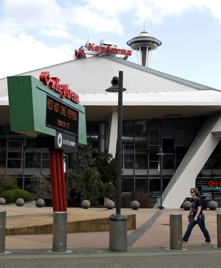 In this March 16, 2017 photo, a pedestrian walks past KeyArena in Seattle. Tim Leiweke, head of the Oak View Group, is expected to submit a proposal for a renovation of KeyArena, which formerly was home to the NBA’s Seattle SuperSonics. Seattle is in the midst of an arena showdown with three groups putting forth proposals around two sites to build the possible future home for teams from in the NBA basketball and NHL hockey leagues. (AP Photo/Ted S.