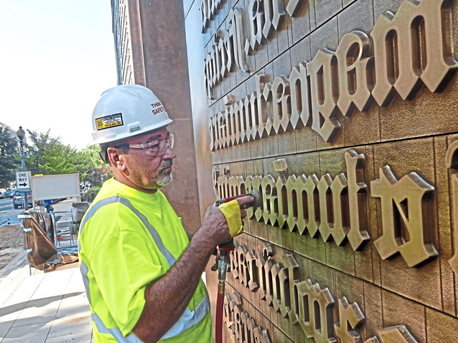 Jack Elliott of the Kansas City foundry Zahner burnishes the 40-foot bronze panels that flank the entrance to the Museum of the Bible in order to age their appearance.