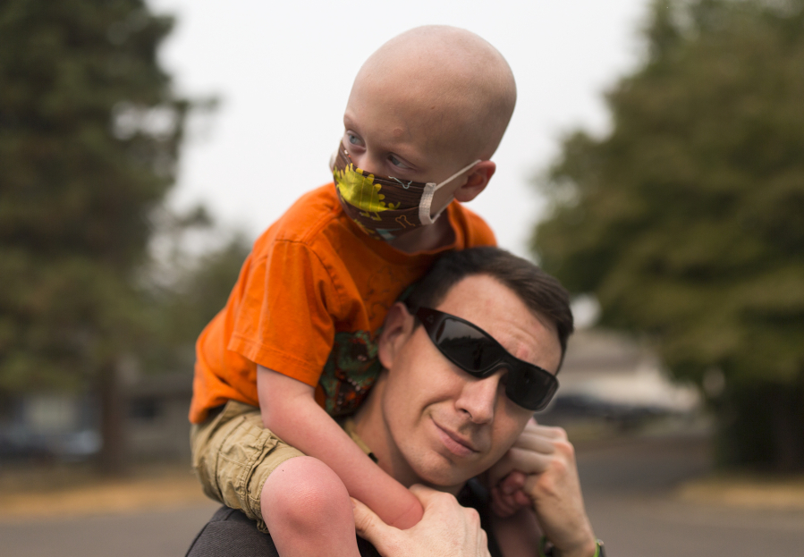 Declan Reagan, 5, sits atop the shoulders of his father, Francis Reagan, Tuesday outside the Washougal Police Department, where his dad serves as a police officer. Declan received a bone marrow transplant in July after being diagnosed with two types of cancer. “A woman in another country gave him the chance to have a life, and that’s really cool” says his mother, Lauren Reagan.