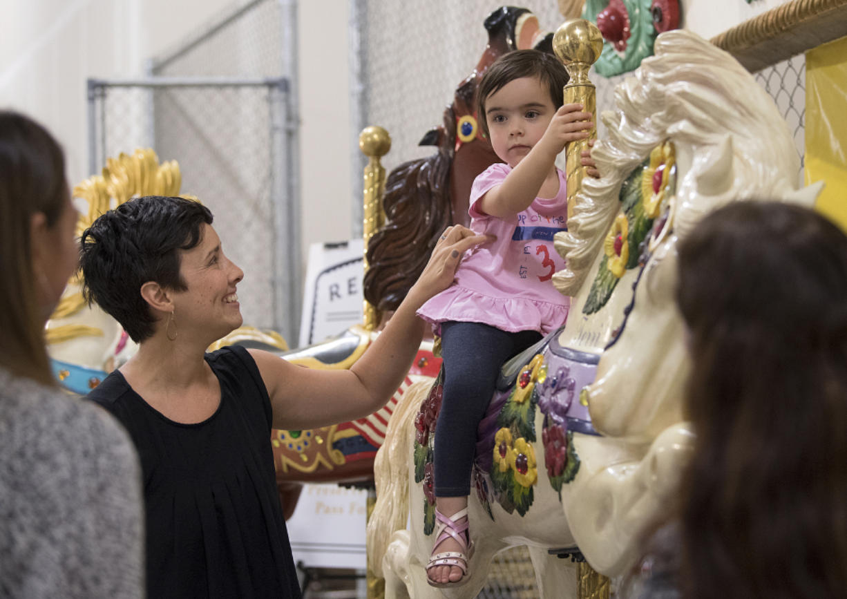 Jessie Burke shares a smile with her daughter, Miette Cohen, 2, as she tries out one of the horses from the historic Jantzen Beach Carousel before a press conference Thursday morning. Restore Oregon has acquired the carousel and hopes to find a permanent location and a group to assume ownership.