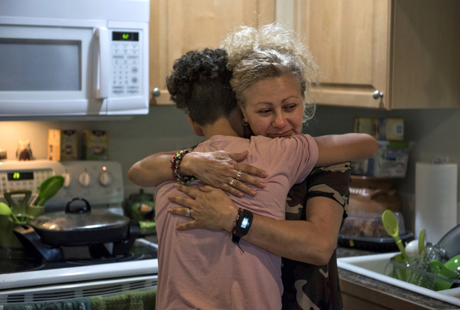 Enedis Flores, 51, hugs her 12-year-old son, Raymond, in their kitchen late this summer at their Vancouver home. The family has been struggling since their father, Ramon Flores-Garcia, was taken into custody by U.S. Immigration and Customs Enforcement agents earlier this year and was deported.