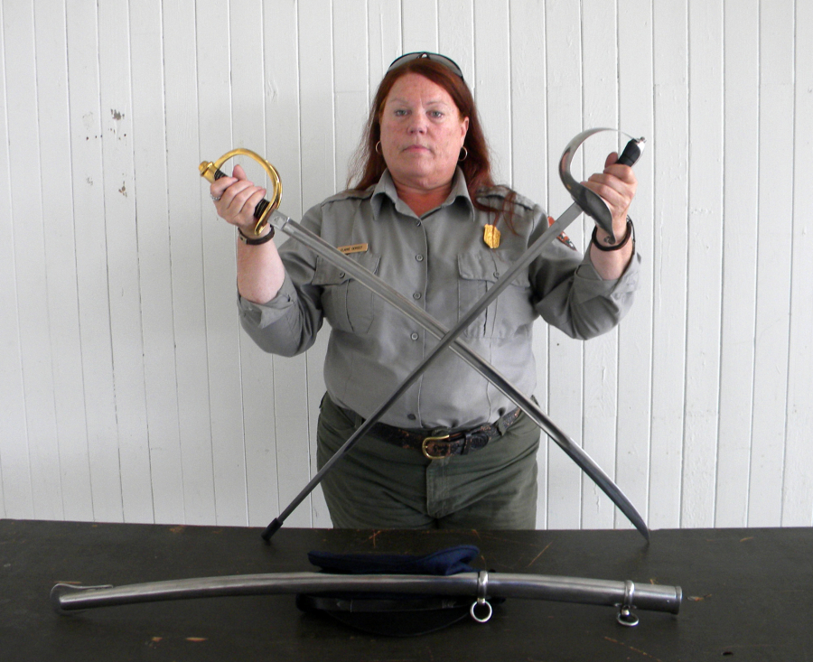 Elaine Dorset, National Park Service archaeologist, with two replica sabers that will help re-enactors represent an Army dragoon unit at Fort Vancouver in the 1850s. The saber with the gold-colored bell guard will be carried by re-enactors. The one with the silver-colored bell guard and rubber tip is a training saber.