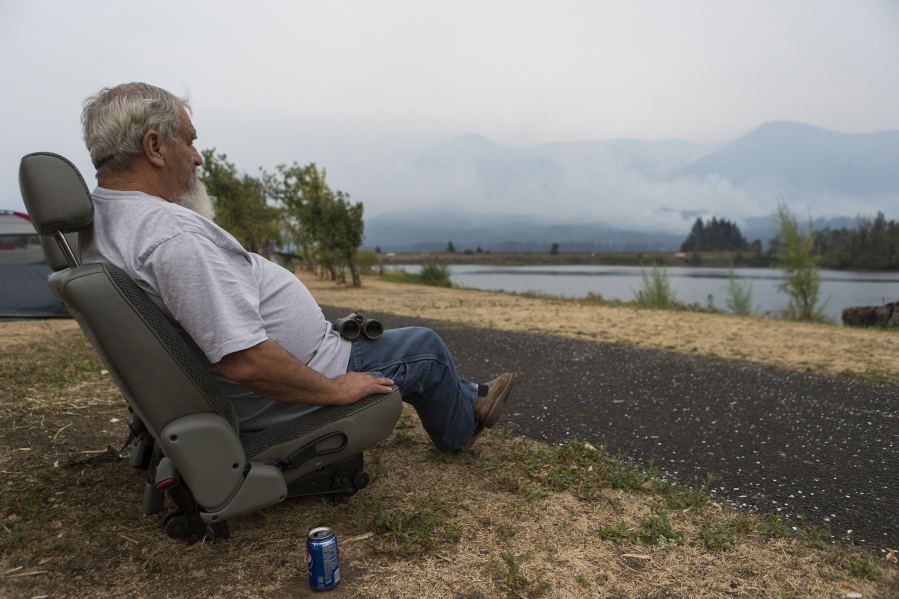Sitting in Stevenson, Robert Loomis of Cascade Locks, Ore. looks at the Eagle Creek fire creeping toward his home on Thursday. Loomis moved to Cascade Locks from Hood River, Ore., just a month ago for a quieter place, but he is worried that he now might have to find another place to live.