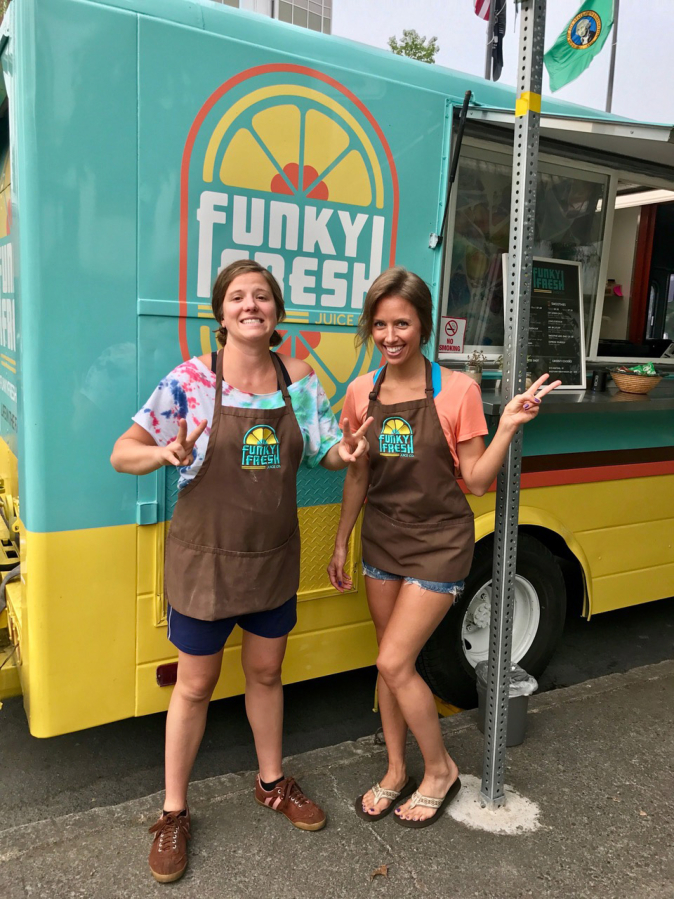 Funky Fresh Juice Company co-owners Mira Alexander, left, and Rebekah Trigg stand in front of the juice truck they started with sisters Shawna Stewart and Morgan Hutchinson.