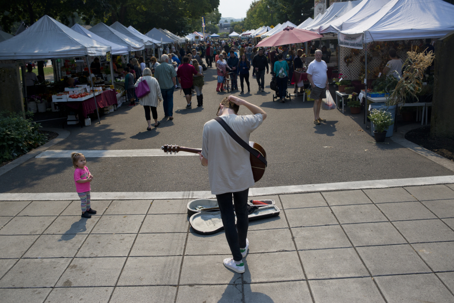 Jack Spadolini, 18, plays cover songs on his guitar for passers-by at the Vancouver Farmers Market on a recent Saturday. Spadolini has been performing at the market for about four years, and plans to use the money on an upcoming work trip to Australia and later for college.