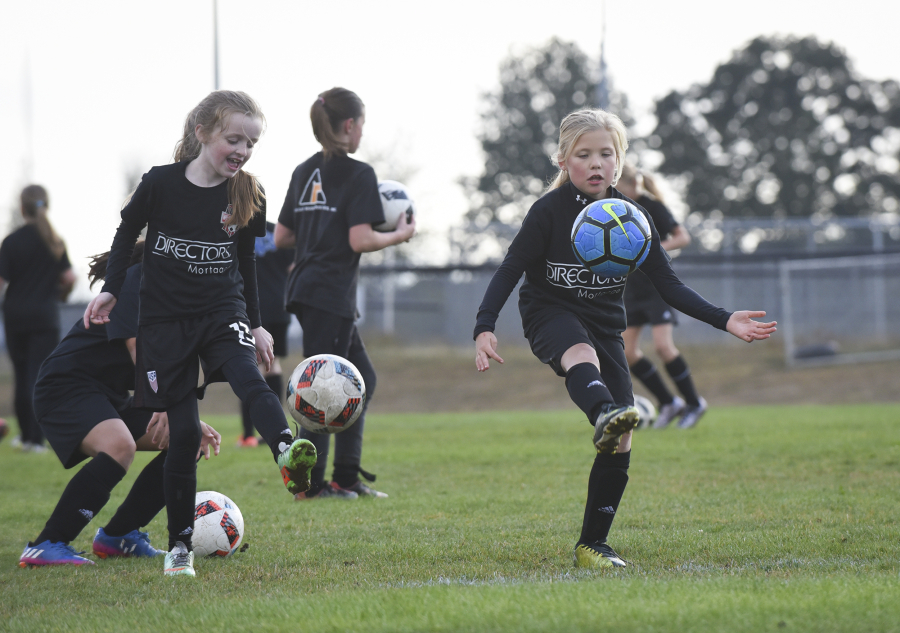 Dicey Delano, left, and Ava Bond practice with third- and fourth-grade Washington Timbers Football Club players Wednesday evening at Harmony Sports Park in the east Vancouver area.