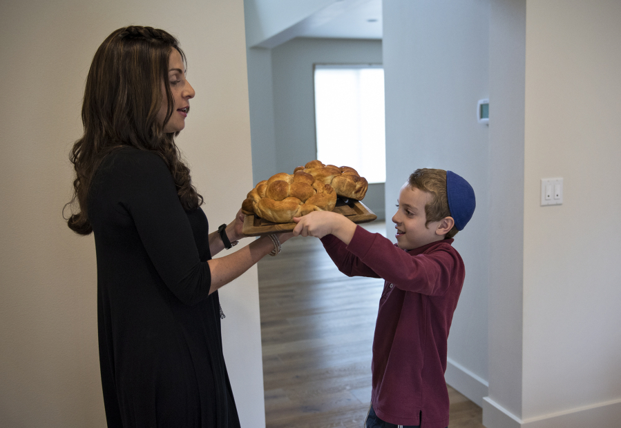 Tzivie Greenberg and her son, Efraim, 8, carry round loaves of challah to the dinner table in preparation for evening celebrations of the first night of Rosh Hashanah, the Jewish New Year, at their home in Vancouver on Wednesday afternoon. While challah is often served throughout the year in braided form, the round shape at the new year represents the cyclical nature of time, and the cinnamon and sugar represent a sweet new year. Tzivie and her husband, Rabbi Shmulik Greenberg, are co-directors of the Chabad Jewish Center in northeast Vancouver.