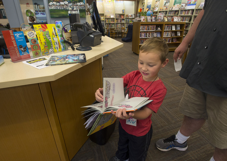 Connor Jackson, 5, of Vancouver flips through a book he checked out Friday after he and his dad, Mike, visited the Washougal Community Library. A new library would include a children’s area. Staffers now must roll bookcases out of the way for story times.