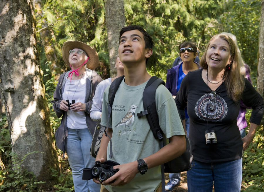 Tyler Hartlauer, 14, a volunteer, listens to a song bird’s call to find its location. Dorrie Estriblu of Vancouver, at right, listens along with Glenda McCune, at left in hat, also of Vancouver.