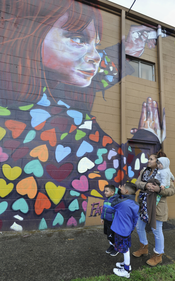 From left, Aiden, Isaiha and Brenda Paz, who is holding Gianni, look at one of the four wall murals recently completed along East Fourth Plain Boulevard. On Saturday, community members came to the Fourth Plain corridor for the Fourth Plain Forward Summer of Murals celebration.
