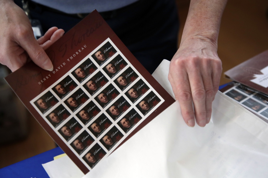 U.S. Postal Service worker Dianne Zambelli places a sleeve of newly dedicated Henry David Thoreau postage stamps for purchase in a bag on May 23 at Walden Pond in Concord, Mass., where the 19th century American philosopher and naturalist spent two years in solitude and reflection. The U.S. Postal Service would need to boost prices for mailing letters and packages by nearly 20 percent if it hopes to have enough cash on hand to avoid bankruptcy. That means the price of a first-class stamp could jump from 49 cents to nearly 60 cents, the biggest one-time increase in its history.