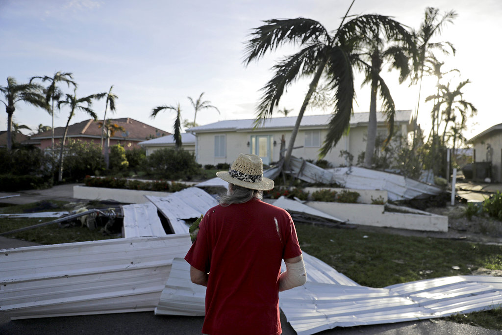 A roof is strewn across a home's lawn as Rick Freedman checks his neighbor's damage from Hurricane Irma in Marco Island, Fla., Monday, Sept. 11, 2017.