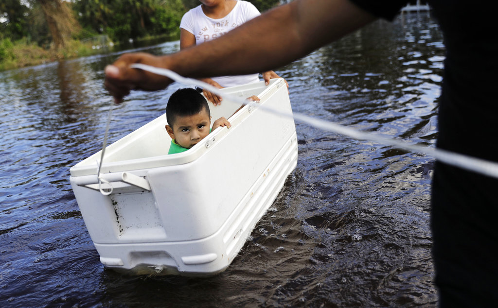 Alfonso Jose Jr., 2, is floated down his flooded street by his parents as the wade through water to reach an open convenience store in the wake of Hurricane Irma in Bonita Springs, Fla., Tuesday, Sept. 12, 2017.