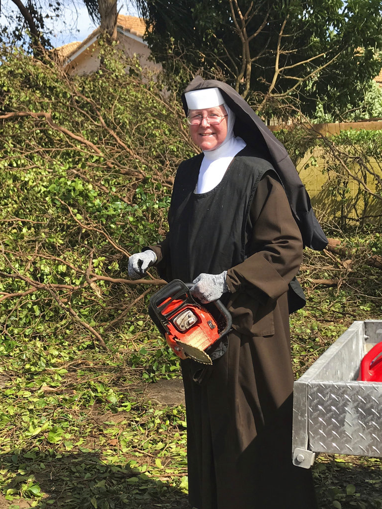 In this Tuesday, Sept. 12, 2017, photo provided by the Miami-Dade Police Department, Sister Margaret Ann holds a chain saw near Miami, Fla. Police said the nun was cutting trees to clear the roadways around Archbishop Coleman Carrol High School in the aftermath of Hurricane Irma.