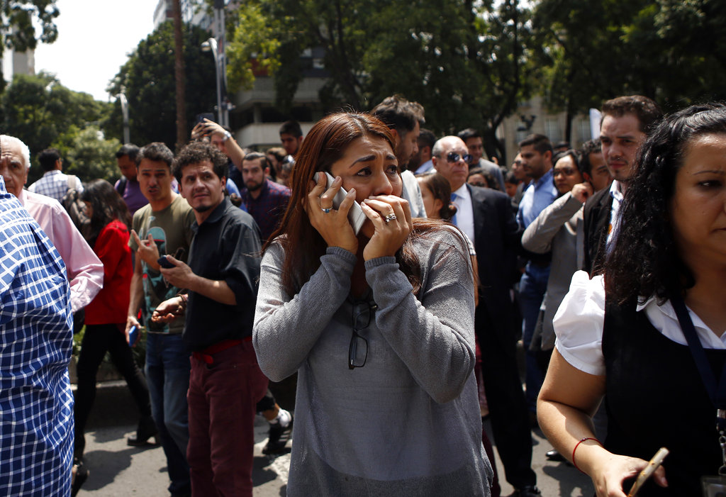 A woman speaks on her cell phone as people evacuated from office building gather in Reforma Avenue after an earthquake in Mexico City, Tuesday Sept. 19, 2017.