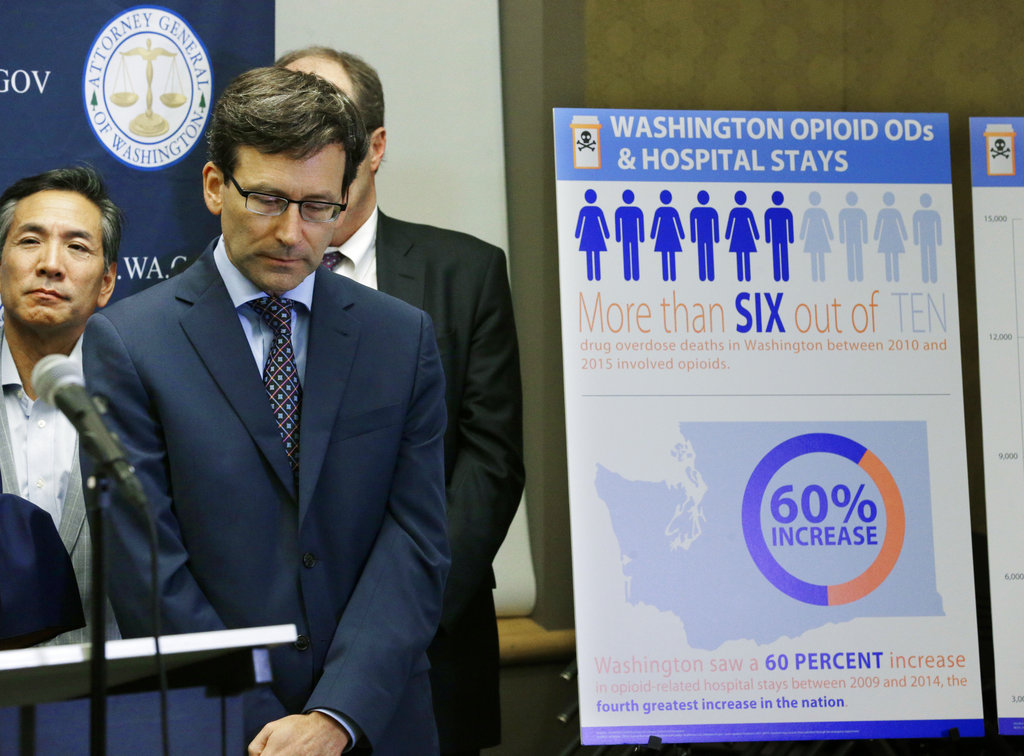Washington Attorney General Bob Ferguson, second from left, listens to a question, Thursday, Sept. 28, 2017, in Seattle, as he stands near a chart detailing increases in overdoses and hospital stays relating to opioid use in Washington state. Ferguson said Thursday that the state and the city of Seattle are filing lawsuits against several makers of opioids, including Purdue Pharma, seeking to recoup costs incurred by government when the drugs -- which many officials blame for a national addiction crisis -- are abused. (AP Photo/Ted S.