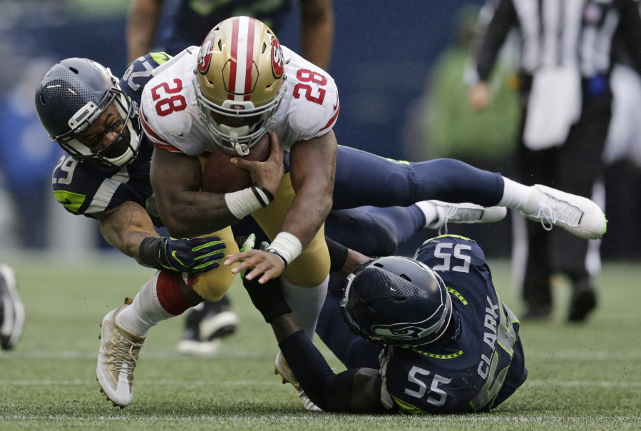 Seattle Seahawks free safety Earl Thomas, left, and defensive end Frank Clark (55) tackle San Francisco 49ers running back Carlos Hyde (28) in the second half of an NFL football game, Sunday, Sept. 17, 2017, in Seattle.