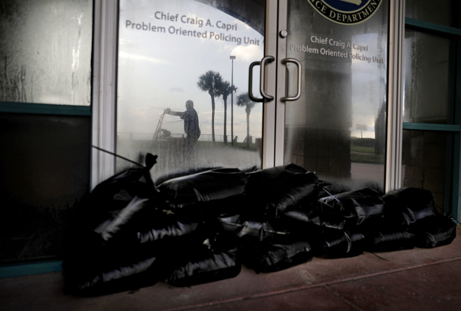 Sandbags sit outside a police station office as a worker secures the grounds of a hotel along the beach ahead of Hurricane Irma in Daytona Beach, Fla., Friday, Sept. 8, 2017. Coastal residents around South Florida have been ordered to evacuate as the killer storm closes in on the peninsula for what could be a catastrophic blow this weekend.