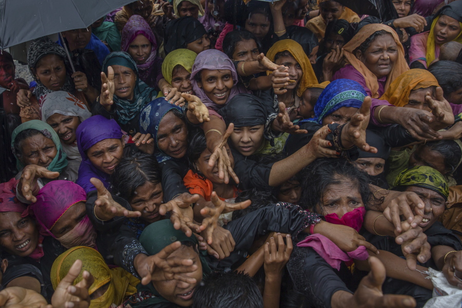 Rohingya Muslim women, who crossed over from Myanmar into Bangladesh, stretch their arms out to collect sanitary products distributed by aid agencies near Balukhali refugee camp, Bangladesh, Sunday, Sept. 17, 2017. Bangladeshi authorities on Sunday took steps to restrict the movement of Muslim Rohingya refugees living in crowded border camps after fleeing violence in Myanmar, while that nation’s military chief maintained the chaos was the work of extremists seeking a stronghold in the country.