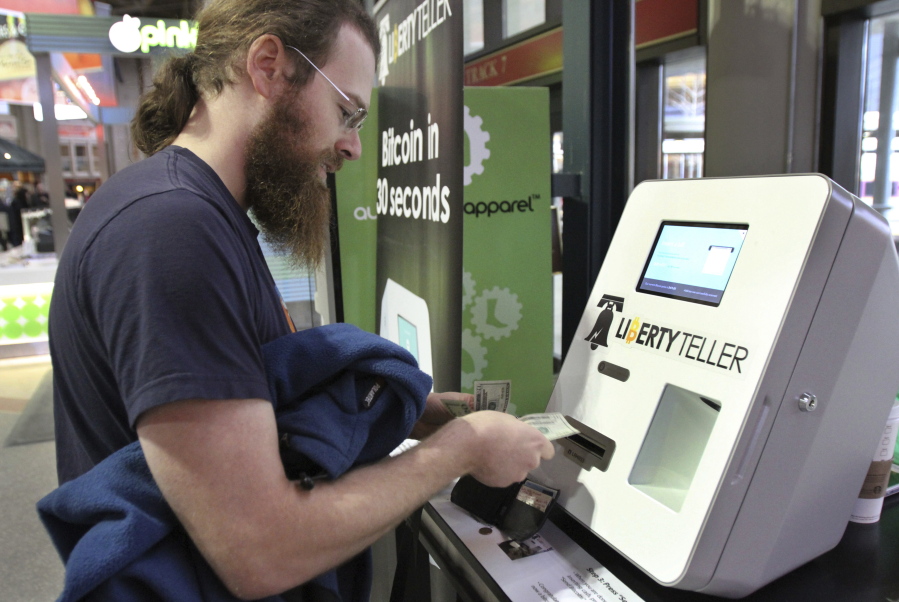 Tim McCormack of Boston inserts cash into a Liberty Teller ATM while purchasing bitcoins in 2014 at South Station train station in Boston. On Thursday, bitcoin tumbled 15 percent to about $3,300 against the dollar.