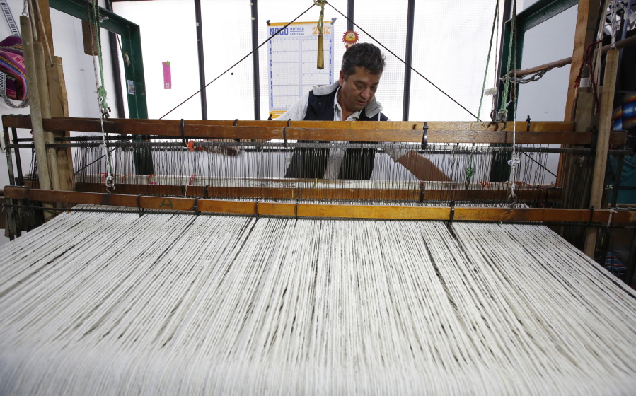 In this Aug., 25, 2017 photo, Carlos Antonio Nino, 57, works in a loom to make ruanas, a traditional Colombian garment, in Nobsa, Colombia. Nino has worked for weeks on a special ruana that he hopes to give to Pope Francis during his upcoming visit to Colombia.