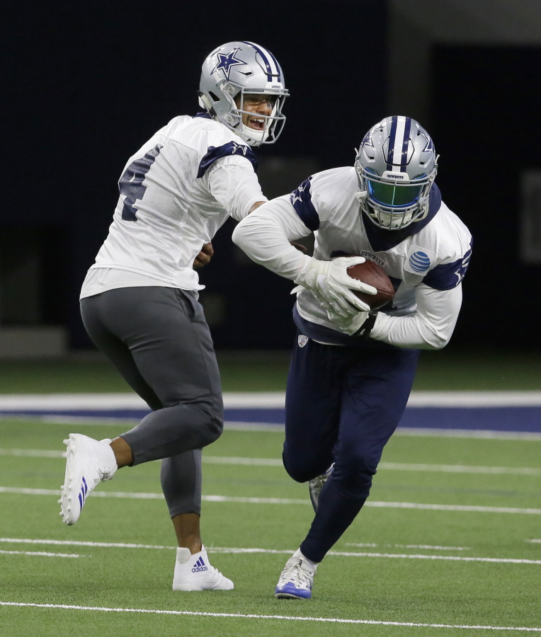 Dallas Cowboys quarterback Dak Prescott (4) hands off to teammate running back Ezekiel Elliott (21) during practice Thursday at Frisco, Texas.