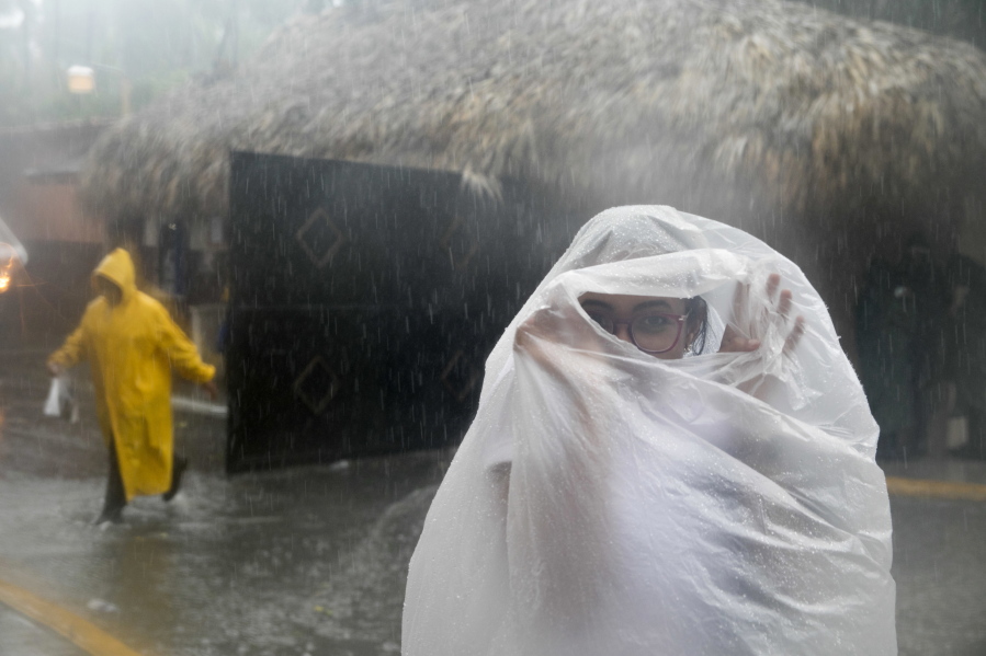 A woman covers herself with a plastic bag as she makes her way to work as Hurricane Maria approaches the coast of Bavaro, Dominican Republic, on Wednesday.