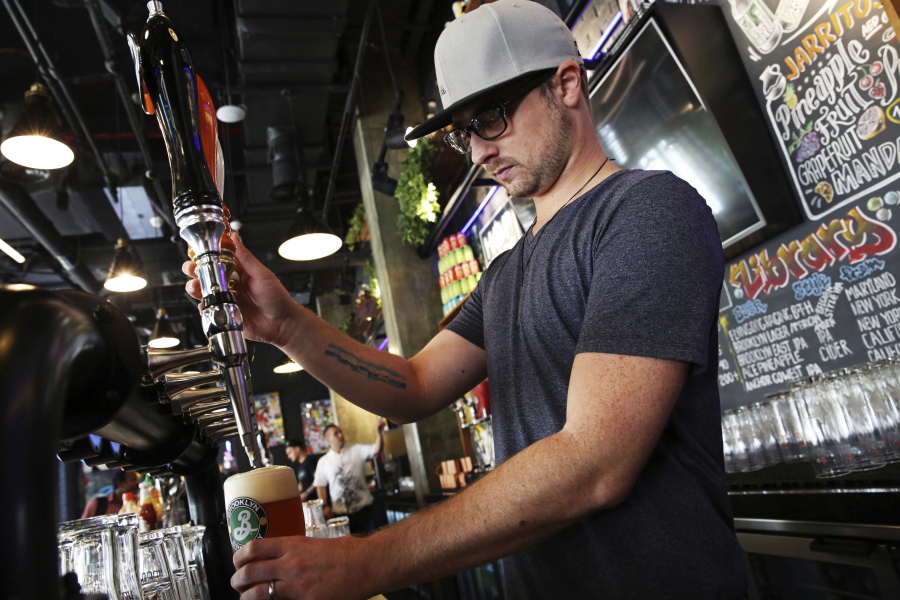 In this Sunday, Sept. 10, 2017 photo, Eric Ballard of Granby, Colorado, the group beverage manager for Sunset Hospitality, pours a beer at the Black Tap restaurant in Dubai, United Arab Emirates. Dubai long has been known for its clubbing scene and cocktail bars, but there’s a new thirst for craft beer. New businesses are springing up and exotic brews are replacing the country’s standard lagers.