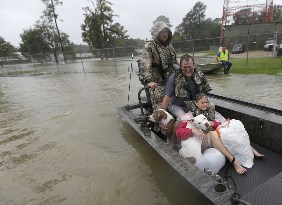 John and Kathy Cservek hold their dogs Lacy and Iggy while being rescued from their home as floodwaters from Tropical Storm Harvey rise in Spring, Texas. The couple saw their dream house in suburban Spring devastated only a little over a year after they bought it. (AP Photo/David J.