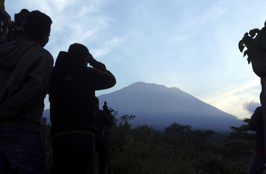 Villagers watch Mount Agung from an observation point which is about 12 kilometers away from the volcano in Karangasem, Bali, Indonesia, on Thursday. The exodus from the menacing volcano on the Indonesian tourist island is nearing 100,000 people, a disaster official said Wednesday, as hundreds of tremors from the mountain are recorded daily.