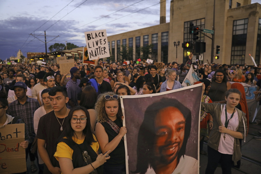 FILE - In this June 16, 2017 file photo, supporters of Philando Castile hold a portrait of Castile as they march along University Avenue in St. Paul, Minn. The vigil was held after St. Anthony police Officer Jeronimo Yanez was cleared of all charges in the fatal shooting last year of Castile. Changes to a Department of Justice program that had reviewed police departments in hopes of building community trust have dismayed some civil rights advocates and left some cities wondering what to do next.
