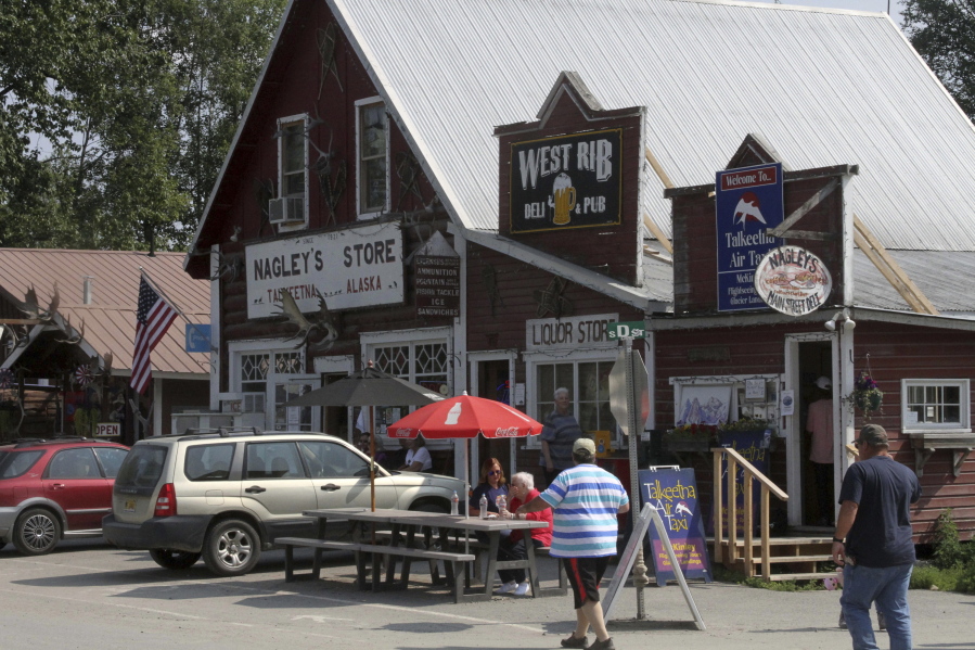 Tourists walk in July along historic Main Street in Talkeetna, Alaska. A new business on Main Street this year is The High Expedition Co., the first marijuana store, and its presence has caused a divide among residents.