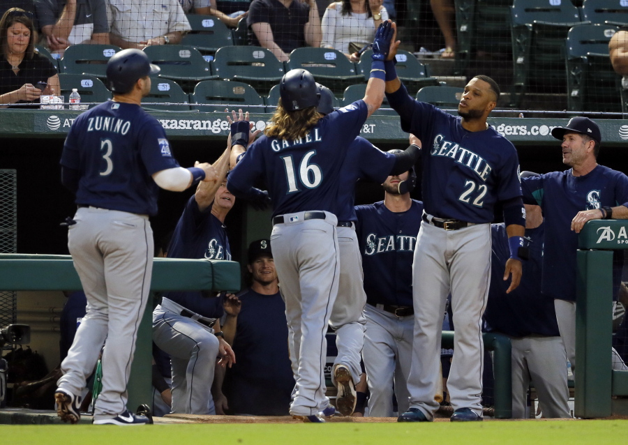 Seattle Mariners’ Ben Gamel (16) is congratulated at the top of the dugout by Robinson Cano (22) after Gamel hit a three-run home run off Texas Rangers’ Miguel Gonzalez that scored Mike Zunino (3) and Yonder Alonso, not seen, during the second inning of a baseball game, Tuesday, Sept. 12, 2017, in Arlington, Texas.