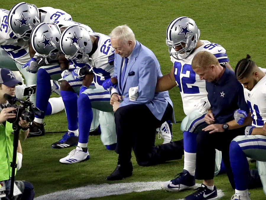 The Dallas Cowboys, led by owner Jerry Jones, center, take a knee prior to the national anthem before an NFL football game against the Arizona Cardinals in Glendale, Ariz. What began more than a year ago with a lone NFL quarterback protesting police brutality against minorities by kneeling silently during the national anthem before games has grown into a roar with hundreds of players sitting, kneeling, locking arms or remaining in locker rooms, their reasons for demonstrating as varied as their methods.