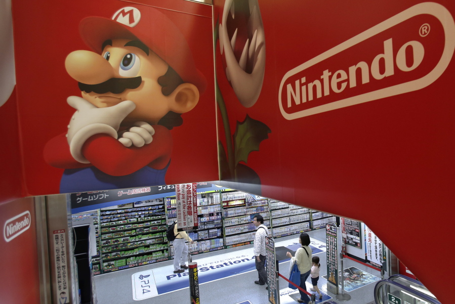 Shoppers walk under the logo of Nintendo and Super Mario characters at an electronics store in Tokyo. Nintendo announced Tuesday that the retro version of its iconic NES video game platform will return to store shelves next year.