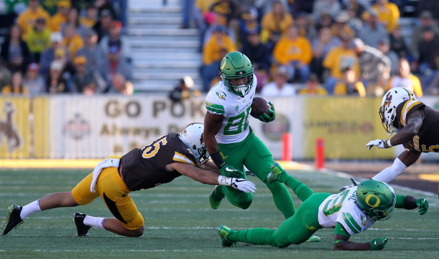 Oregon wide receiver Johnny Johnson III trips over runs past an attempted tackle from Wyoming linebacker Adam Pilapil (45) while Oregon wide receiver Darrian McNeal (89) blocks Wyoming cornerback Rico Gafford (5) during the first half of an NCAA college football game in Laramie, Wyo., Saturday, Sept.16, 2017.
