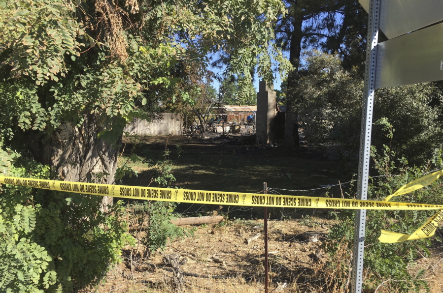 Crime tape seals off a home that burned early Thursday in Meridian, Idaho. Idaho authorities responding to a home invasion Wednesday night shot at the suspect who ran back inside the house minutes before it caught fire. Two people were found dead at the scene and one died later.