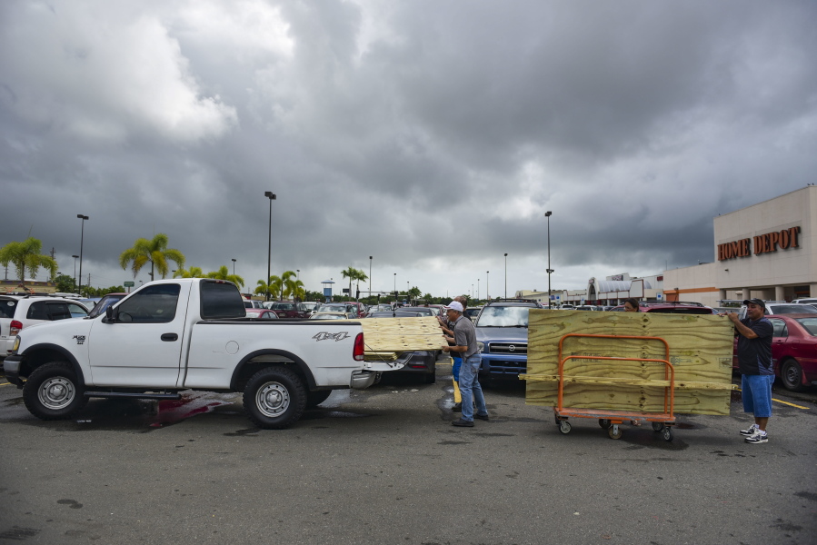 Men load recently purchased wood panels to be used for boarding up windows in preparation for Hurricane Irma, in Carolina, Puerto Rico, Tuesday. Irma grew into a dangerous Category 5 storm, the most powerful seen in the Atlantic in over a decade, and roared toward islands in the northeast Caribbean Tuesday.
