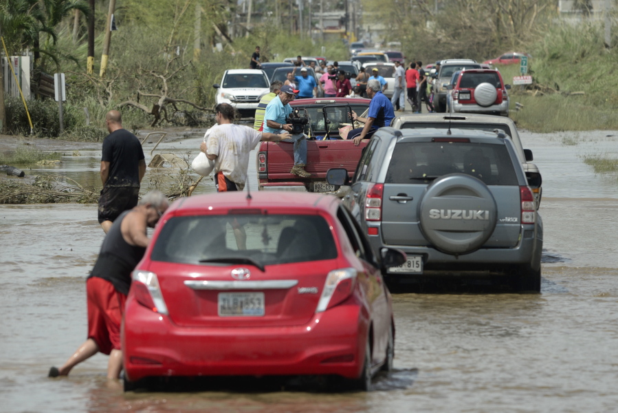 People drive through a flooded road Friday in Toa Baja, Puerto Rico. Thousands were evacuated from Toa Baja after the municipal government opened the gates of the Rio La Plata Dam.