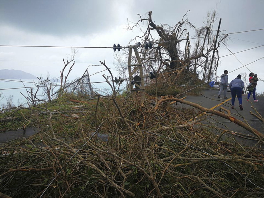 In this Thursday, Sept. 8, 2017 photo, a resident ducks under a downed power line in the aftermath of Hurricane Irma in Tortola, in the British Virgin Islands. Irma scraped Cuba’s northern coast Friday on a course toward Florida, leaving in its wake a ravaged string of Caribbean resort islands strewn with splintered lumber, corrugated metal and broken concrete.