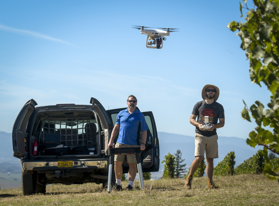 Michael Wing, director of the Aerial Information Systems Laboratory at Oregon State University, left, and doctorate student Cory Garms fly two survey fights with a DJI Phantom Pro 4 unmanned vehicle at a vineyard near Amity, Ore.