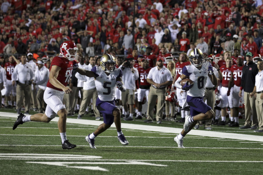 Washington wide receiver Dante Pettis (8) runs a punt-return for a touchdown as as Andre Baccellia (5) blocks Rutgers punter Ryan Anderson during the first half of an NCAA college football game Friday, Sept. 1, 2017, in Piscataway, N.J.