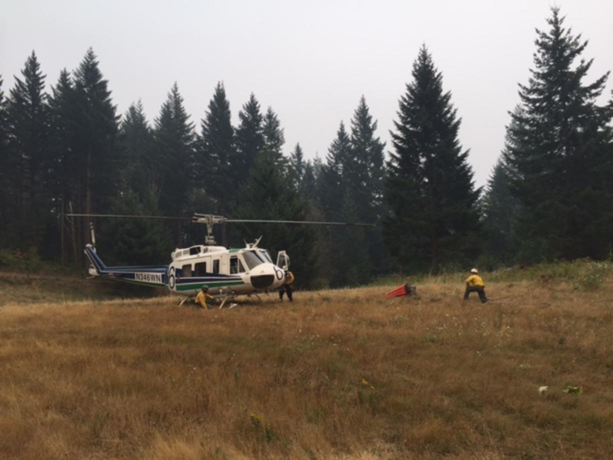 A helicopter crew prepares to make water drops on the Archer Mountain Fire in this image released Saturday by the Washington Department of Natural Resources.