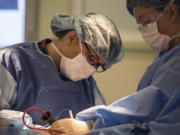 Dr. Toni Storm-Dickerson, left, and certified surgical technologist Autumn Hallcraft work together during a lumpectomy surgery at PeaceHealth Southwest Medical Center.