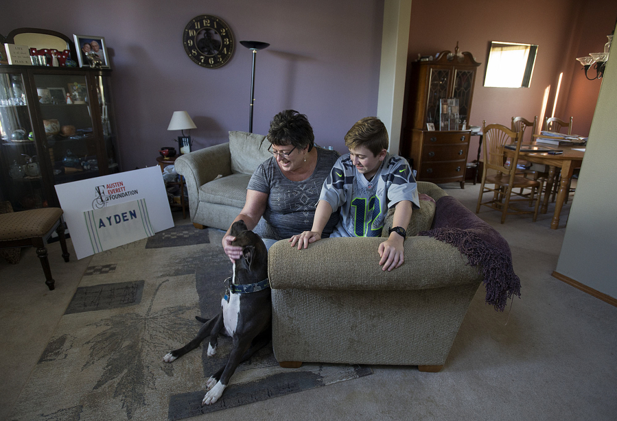 Carole Mills of Vancouver, left, and her son, Ayden, 14, share a moment with their dog, Lena, at their home on Sept. 26. Ayden, who was diagnosed with lymphoma last year, and his mom will be among the thousands participating in the Leukemia & Lymphoma Society’s Light the Night walk this weekend.
